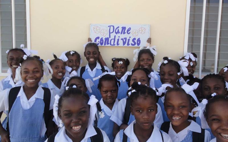Gruppo di bambine con in mano cartello con scritto Pane Condiviso
